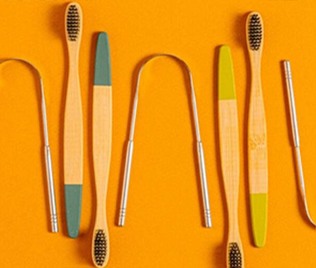 Bamboo dental care tools laid out on an orange background